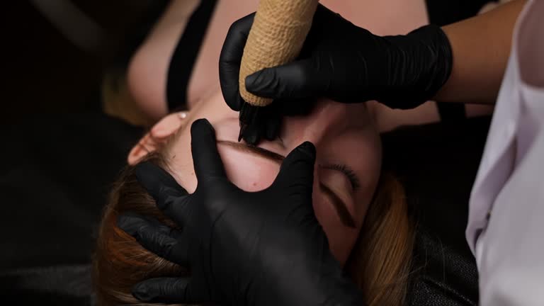 Detailed view of eyebrow tattooing on a young woman's face. Permanent eyebrow makeup, performing eyebrow tattoo PMU